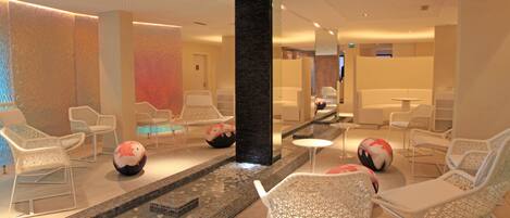 A modern lounge area with white chairs, a small pool, and decorative balls.