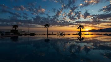 Una piscina al aire libre, sombrillas, sillones reclinables de piscina