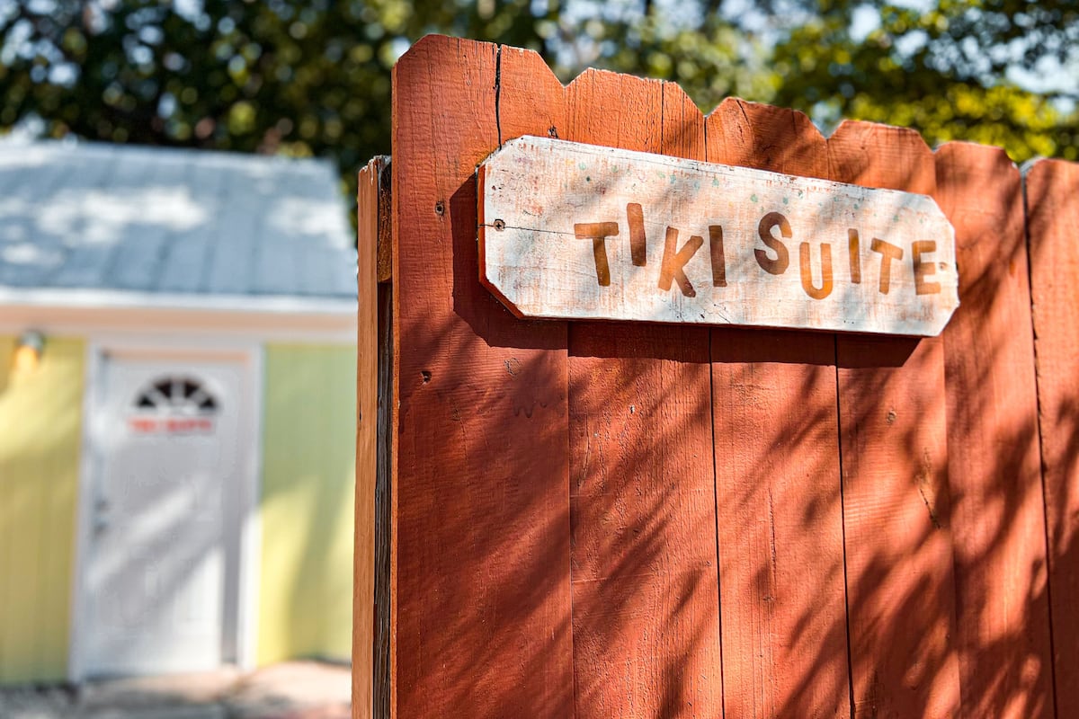 A wooden sign with the text "TIKI SUITE" on a wooden fence.