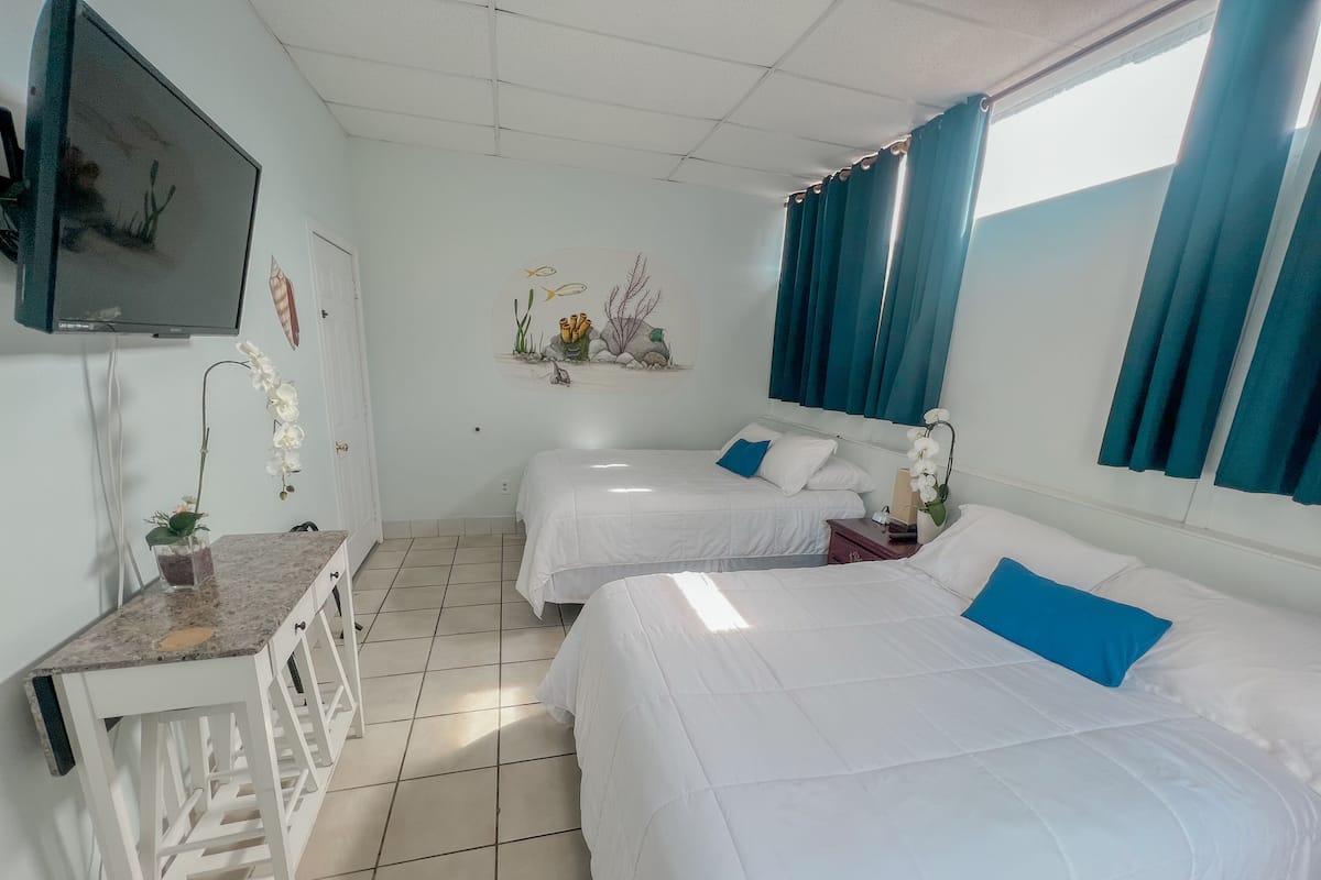 A hotel room with two beds, a desk, a TV, and a decorative wall piece.