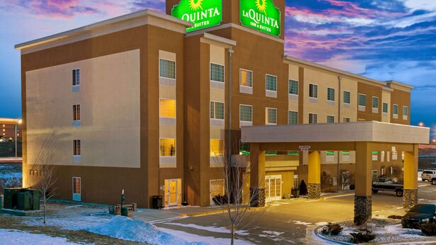 Ein Hotel mit einem gut sichtbaren Schild 'Quinta Inn & Suites', einer überdachten Einfahrt und einem Parkplatz.