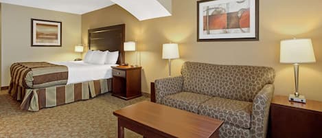 Una habitación de hotel con una cama, un sofá, una mesa y dos lámparas.