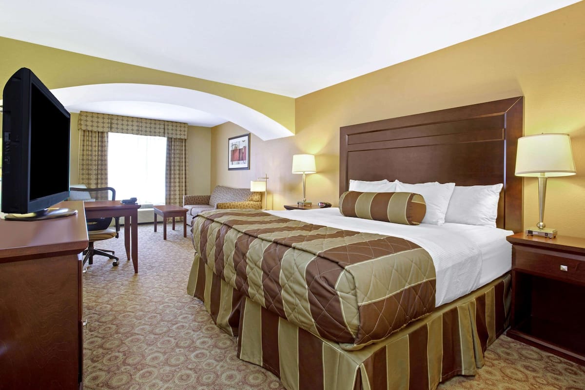 A hotel room with a large bed, a desk, a television, and two bedside lamps.