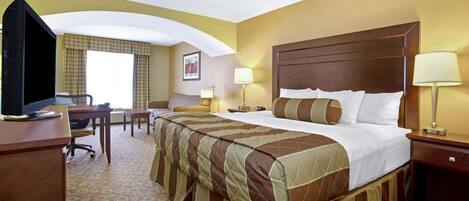 A hotel room with a large bed, a desk, a television, and two bedside lamps.
