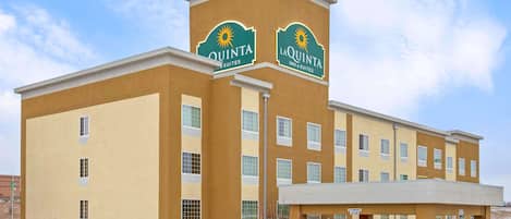 Un hotel con un llamativo letrero que dice 'Quinta', varias ventanas y una entrada cubierta.