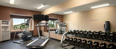 A gym with treadmills, an elliptical, a bench, and a rack of dumbbells.