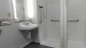Un baño con lavamanos blanco, espejo y cabina de ducha de vidrio.