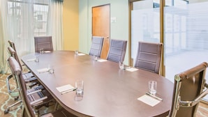 A conference room with a large oval table, six chairs, and a door. - Wingate by Wyndham Bossier City, LA (Bossier City)
