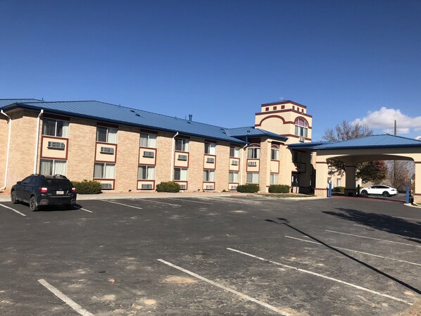 A multi-story hotel with a parking lot and covered parking area.