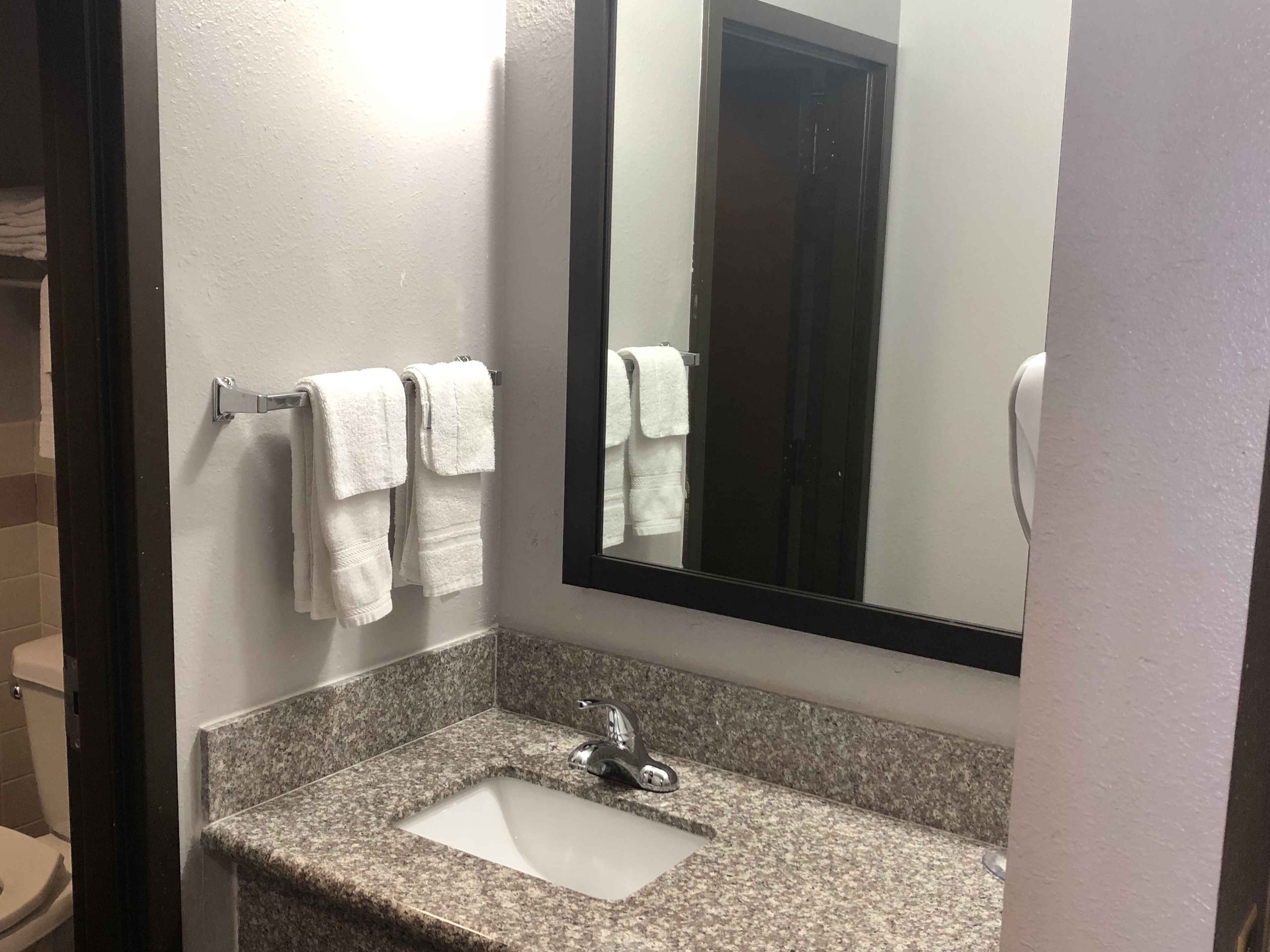 Un bany amb un lavabo de superfície de granat, un mirall i dues tovalloles blanques penjades d'un suport.