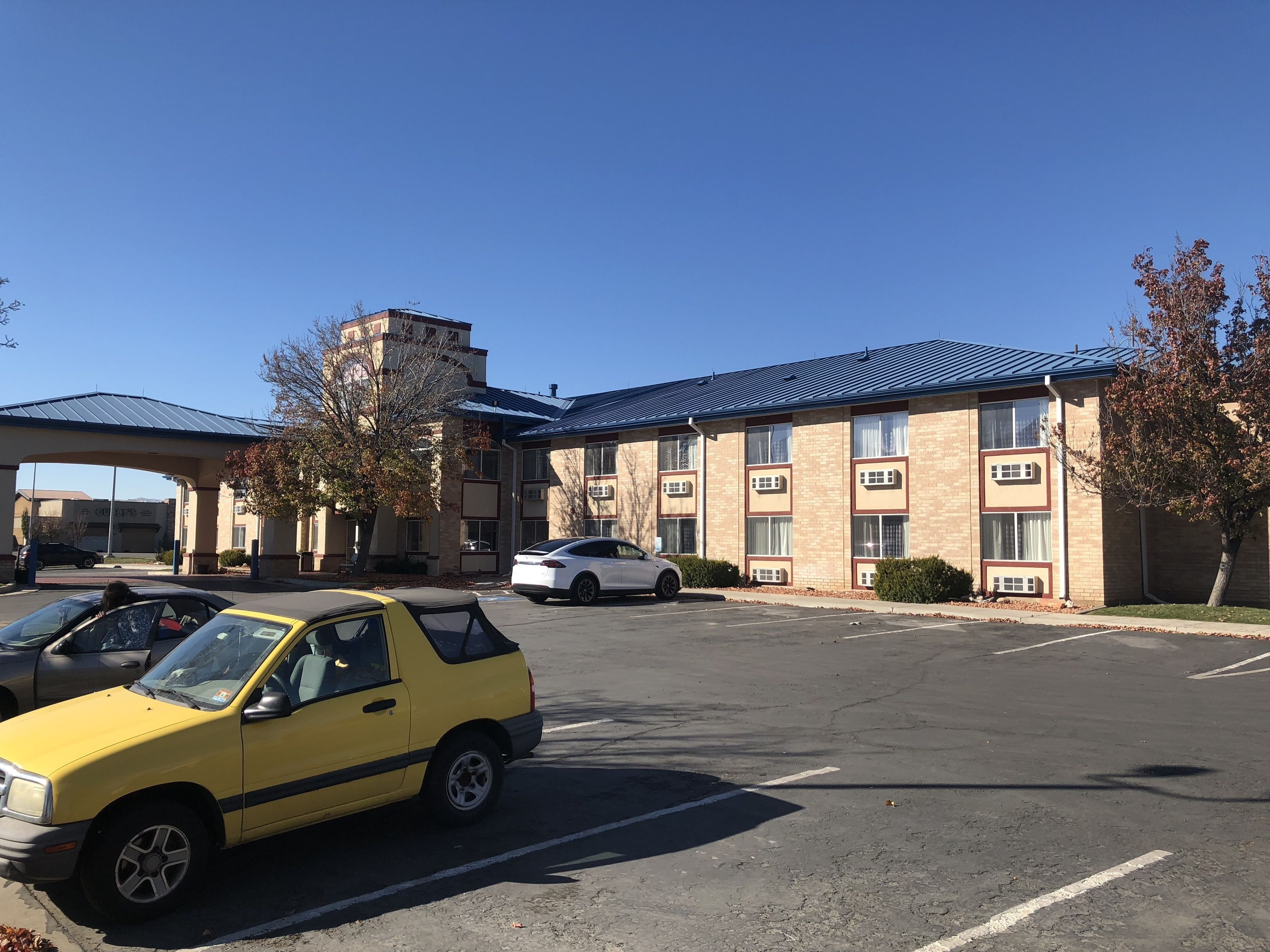 A parking lot with several cars, a building with a blue roof, and a sign that reads "Guthrie's".