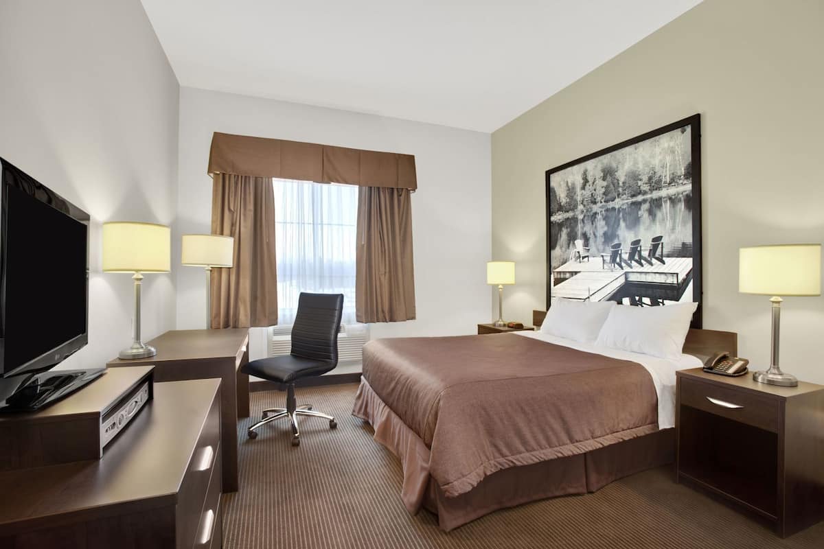 Ein Hotelzimmer mit Bett, Schreibtisch, Fernseher und einem großen Gemälde an der Wand.