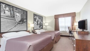 Ein Hotelzimmer mit zwei Betten, einem Schreibtisch mit Fernseher und großen Schwarzweißfotos an der Wand.