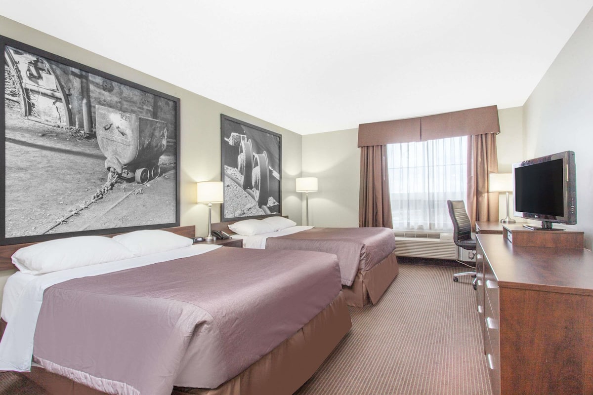 Ein Hotelzimmer mit zwei Betten, einem Schreibtisch mit Fernseher und großen Schwarzweißfotos an der Wand.