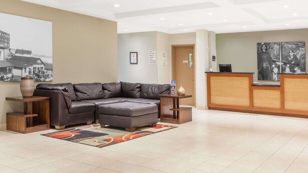 Eine moderne Lobby mit einer Ledersofa, einem Holztresen und einem großen gerahmten Bild an der Wand.