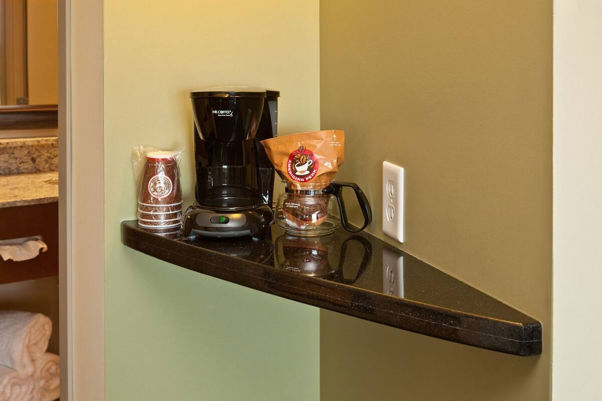 Un plan de travail de cuisine avec une machine à café, un paquet de capsules de café et un bocal rempli de grains de café.