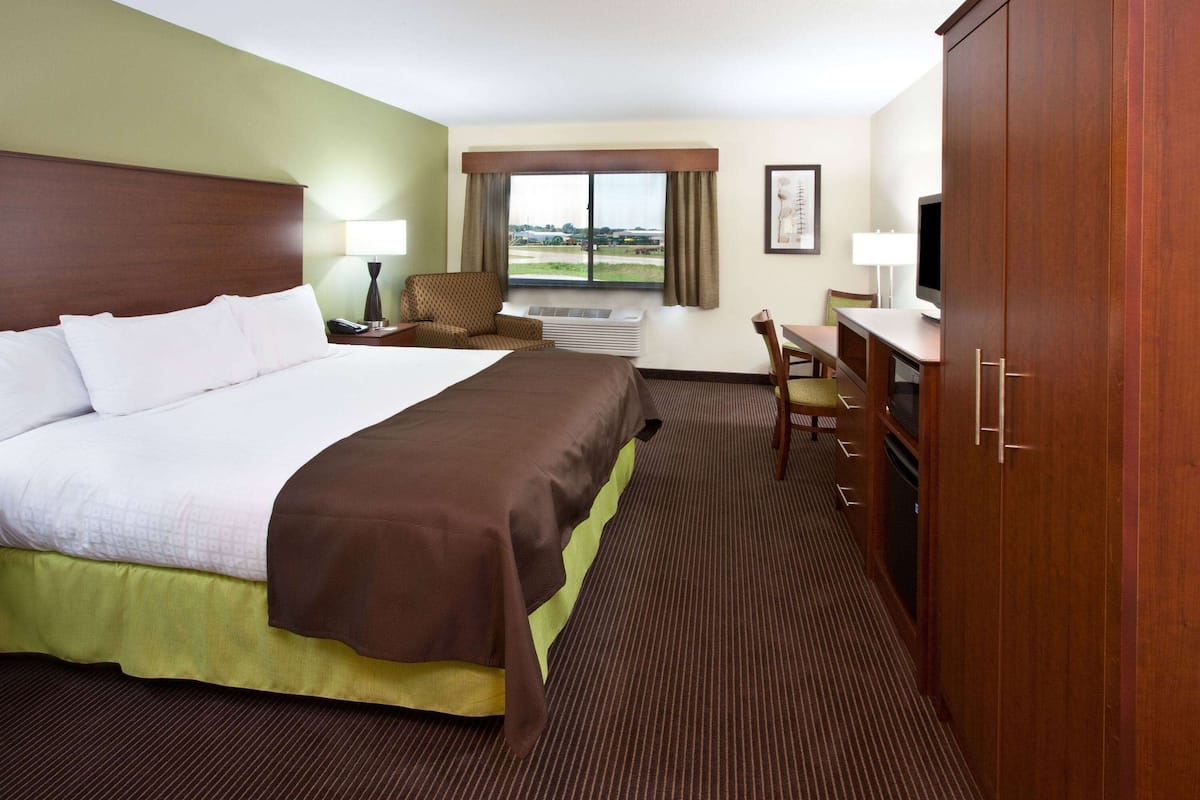 Une chambre d’hôtel équipée d’un grand lit, d’un bureau, d’une chaise, d’un climatiseur et d’un téléviseur.