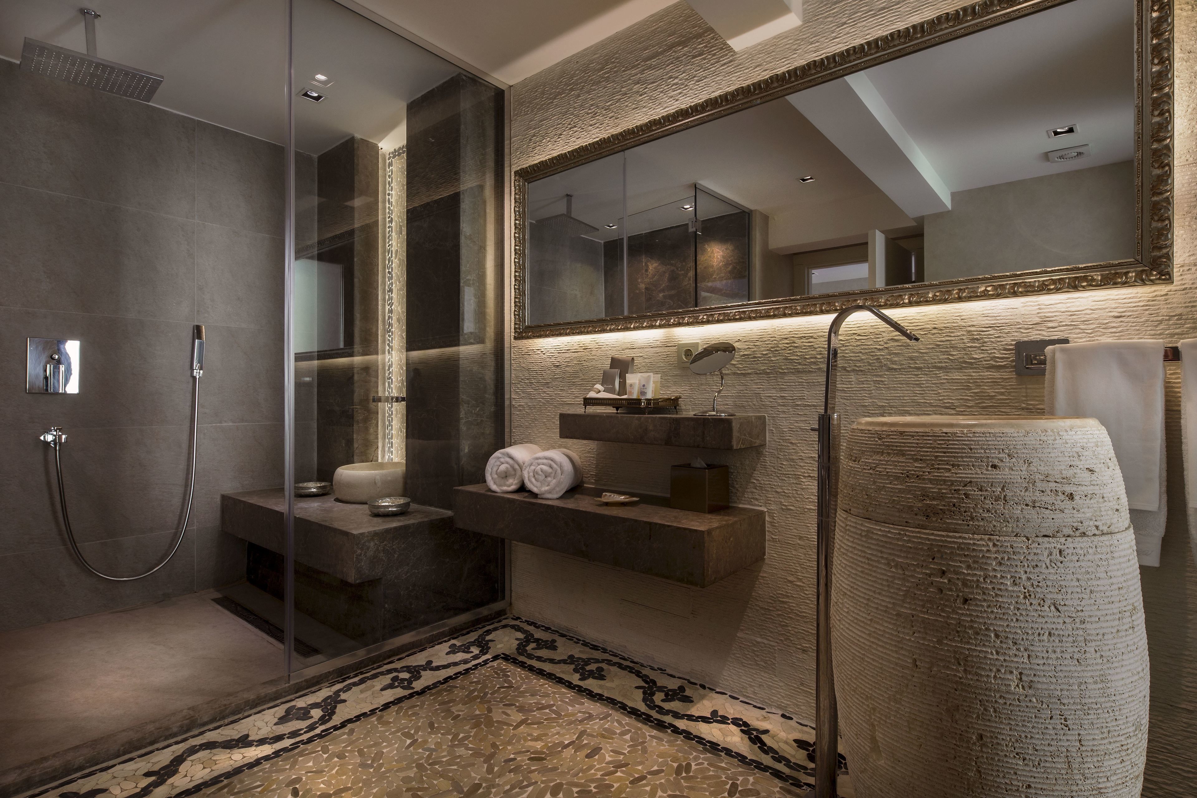A modern bathroom with a glass-enclosed shower, a large mirror, and a textured wall.