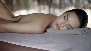 A person lying on a massage table with a towel, in a room with a blurred background.