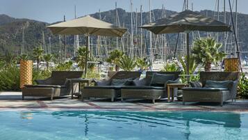 Een buitenzwembad, parasols bij het zwembad en ligstoelen