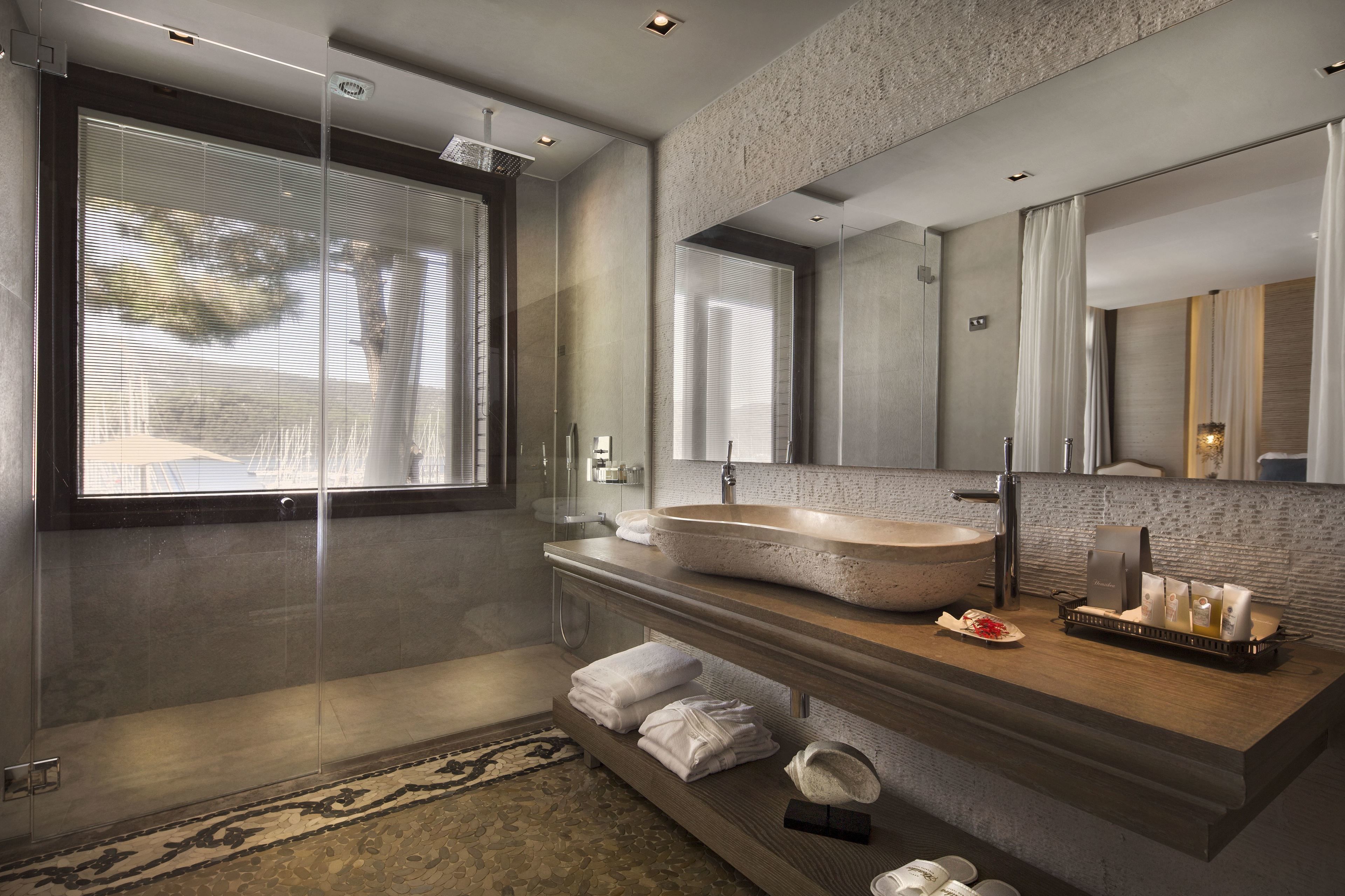 A modern bathroom with a large mirror, a stone sink, and a glass shower enclosure.