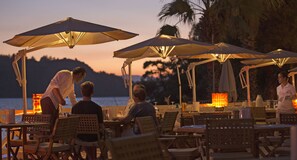 Un restaurante frente al mar, con mesas al aire libre y sombrillas.