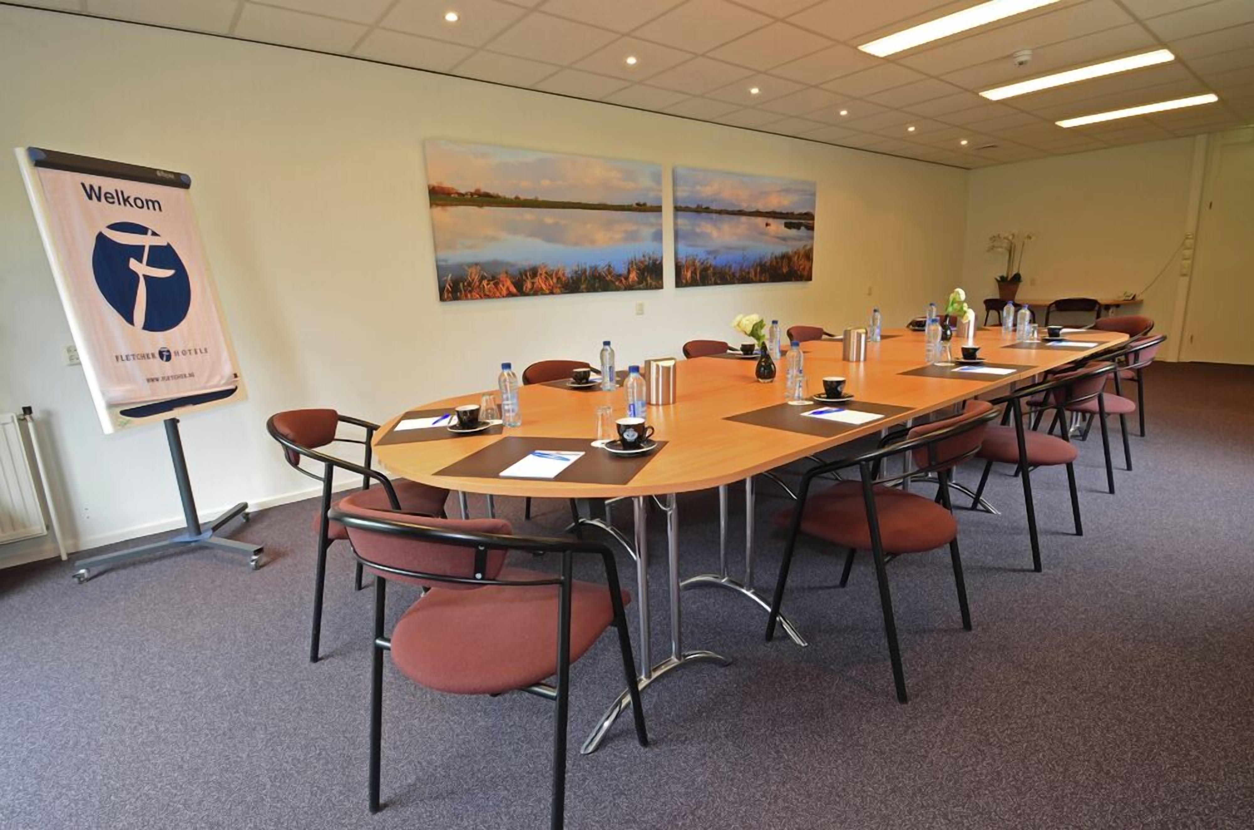 A conference room with a long table, chairs, water bottles, and a welcome banner.