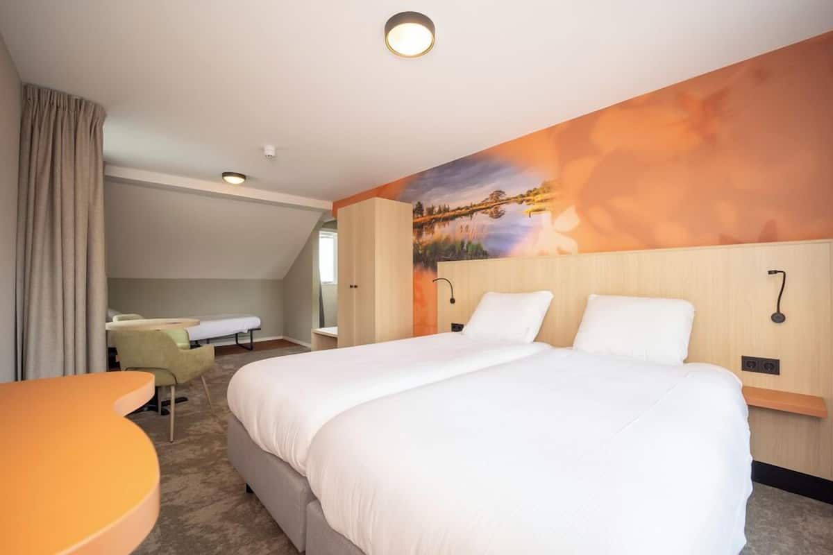 Ein Hotelzimmer mit einem großen Bett, einem Schreibtisch und einem Stuhl.