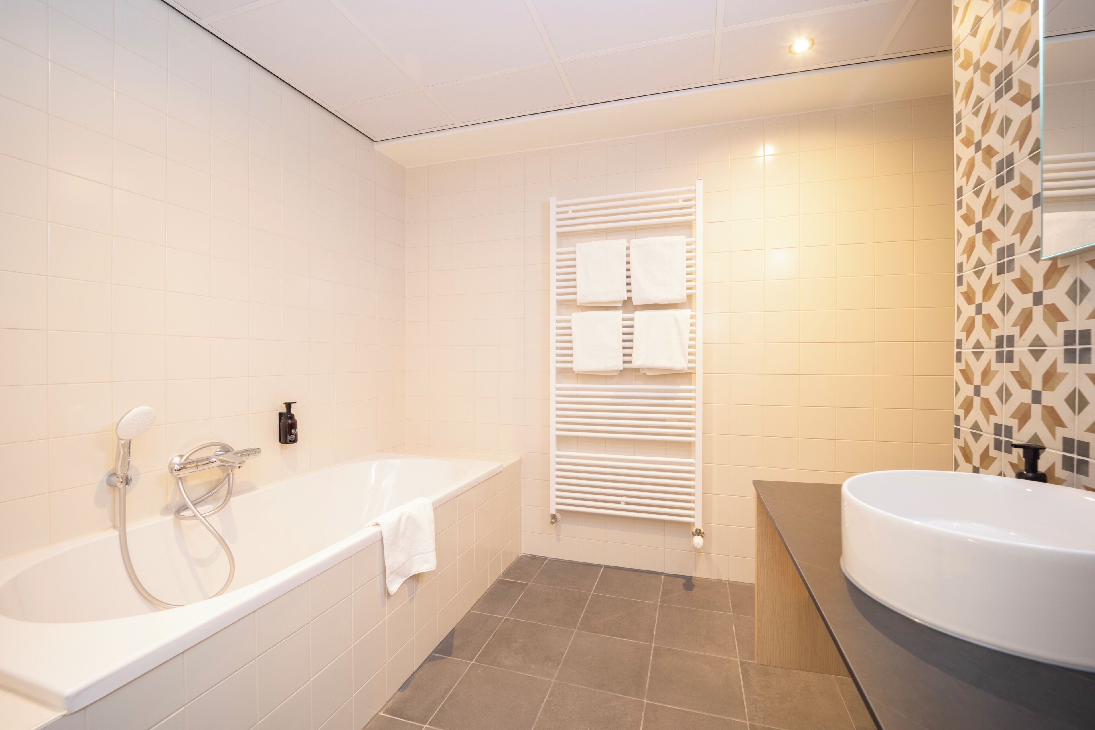 A modern bathroom with a freestanding bathtub, a separate sink, and a towel rack.