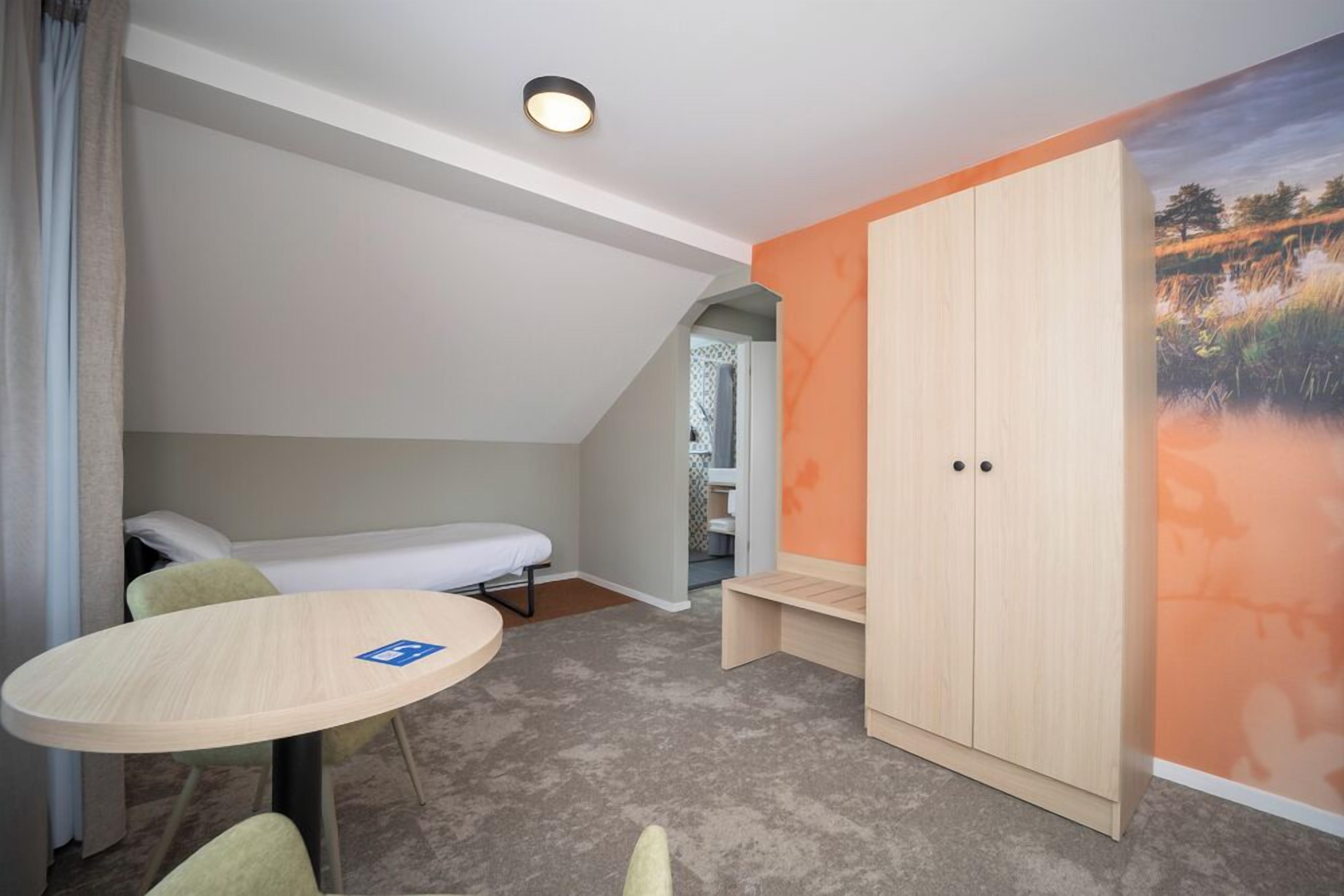 Una habitación pequeña con cama, una mesita y un armario.