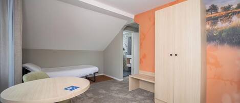 A compact room with a bed, a small table, and a wardrobe.