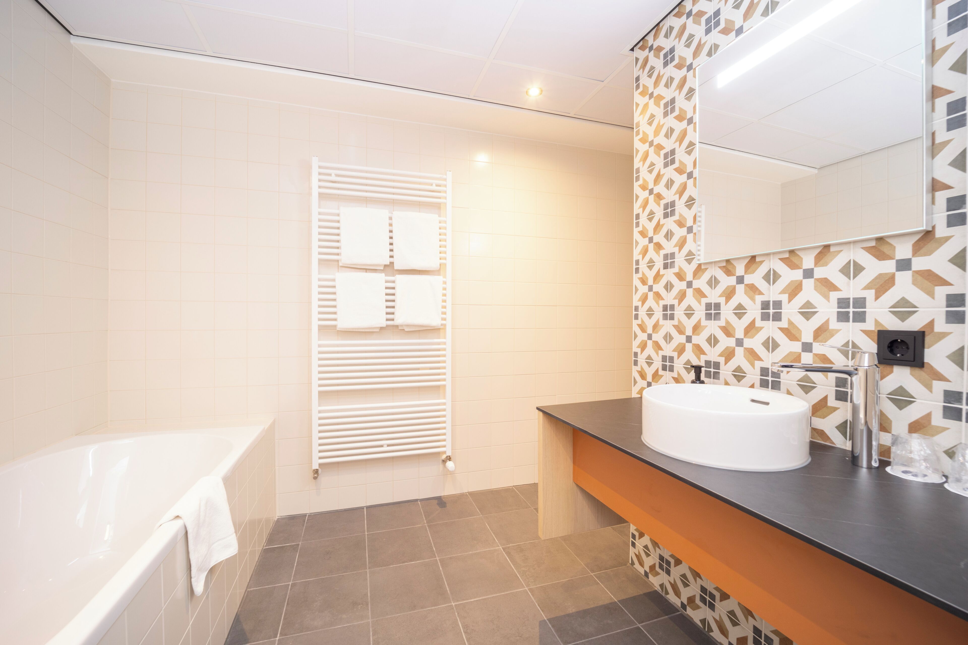 A modern bathroom with a bathtub, a vanity with a sink, and a towel rack.