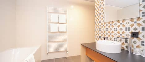 A modern bathroom with a bathtub, a vanity with a sink, and a towel rack.