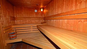 Una sauna con bancos de madera y un cubo de madera.