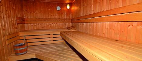 Una sauna con bancos de madera y un cubo de madera.