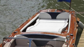 A wooden motorboat docked at a pier with a flag and a flagpole.