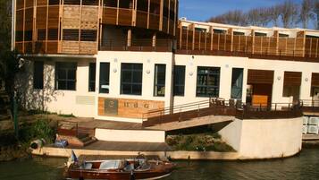 Un edificio moderno con fachada de madera, un muelle con un barco y un cartel que dice