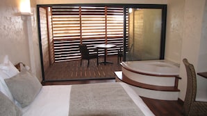 Un dormitorio con una cama grande, una mesita, una silla y una bañera.