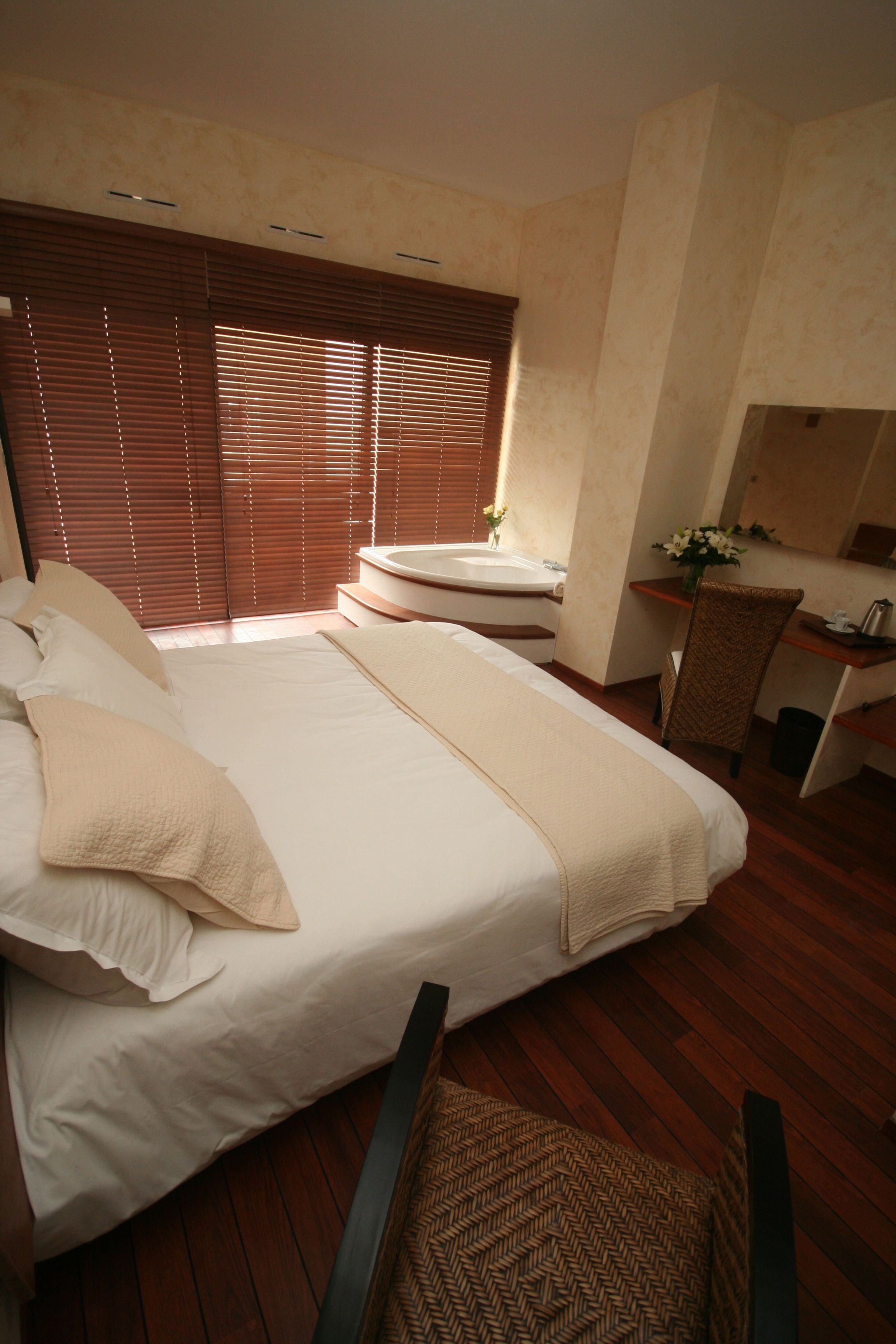A bedroom with a large bed, a desk, and a chair.
