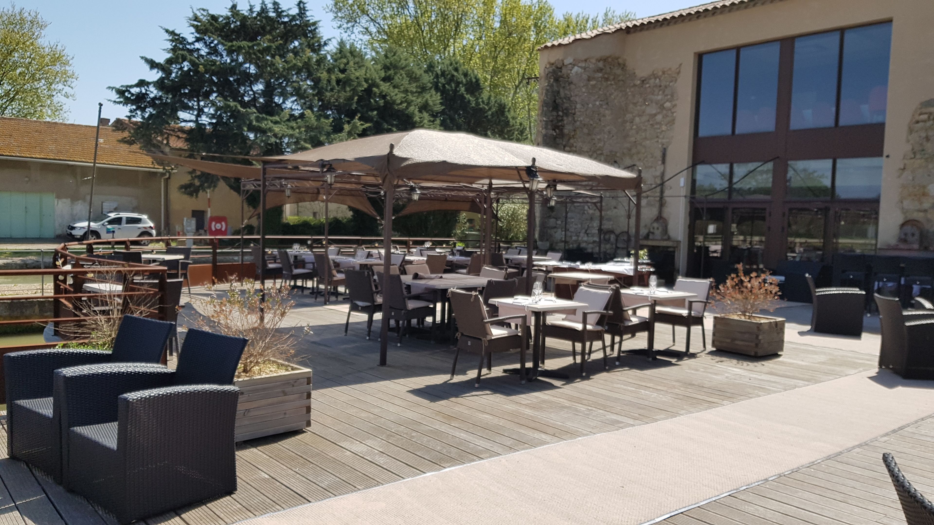 Un patio al aire libre con mesas, sillas, sombrillas y plantas en macetas.