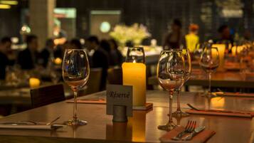 A restaurant setting with tables set for dining, a candle centerpiece, and a 'Réservé' sign indicating a reserved table.