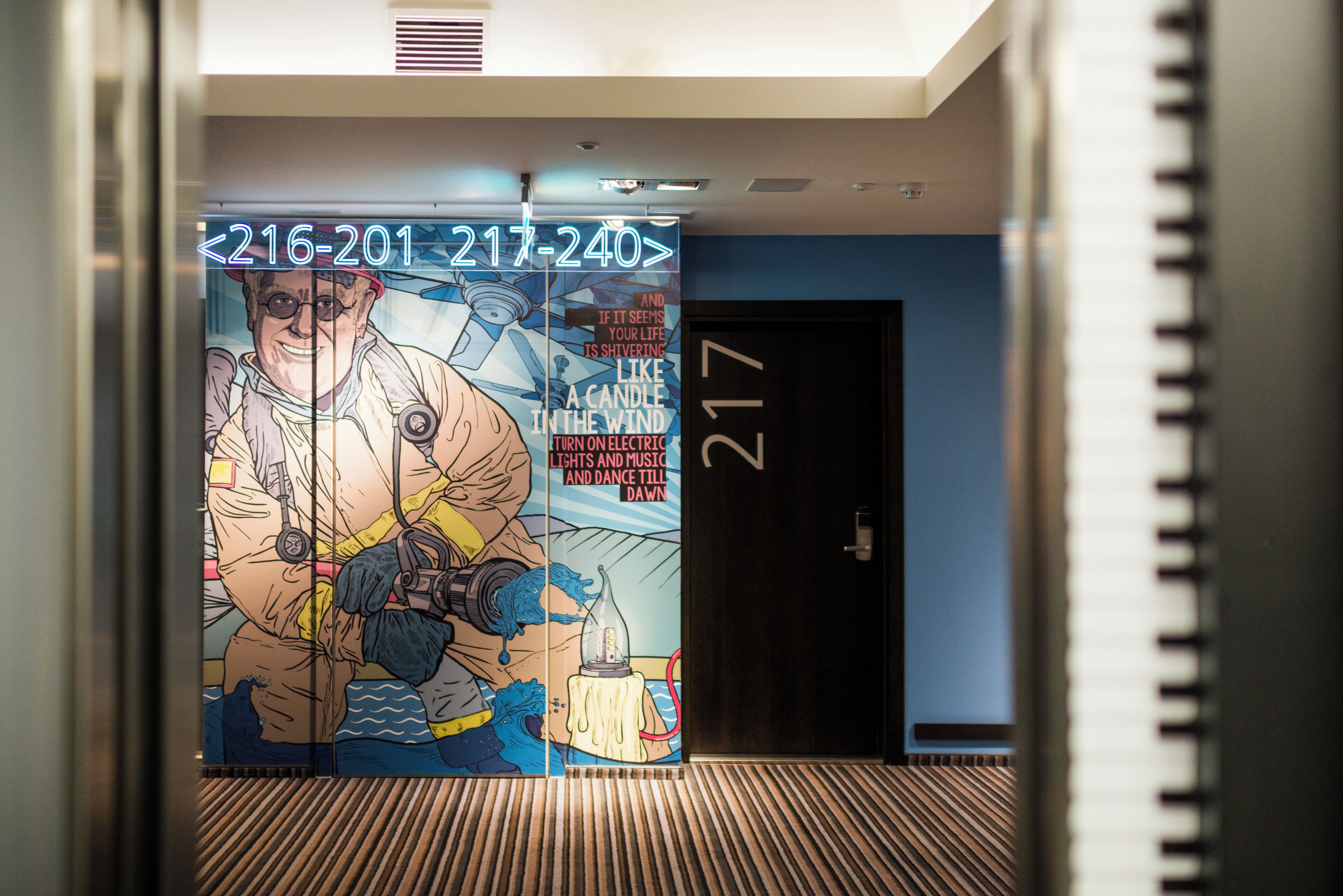 A hallway with a large mural featuring a firefighter and a candle. The number 217 is visible on the wall.
