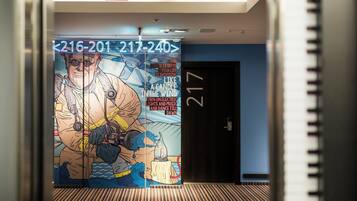 A hallway with a large mural featuring a firefighter and a candle. The number 217 is visible on the wall.