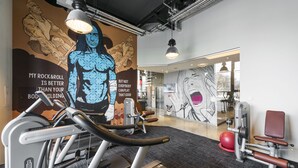 A gym with exercise equipment, a large motivational mural, and a mirror reflecting the interior. - Comfort Hotel LT - Rock 'n' Roll Vilnius (Vilnius)