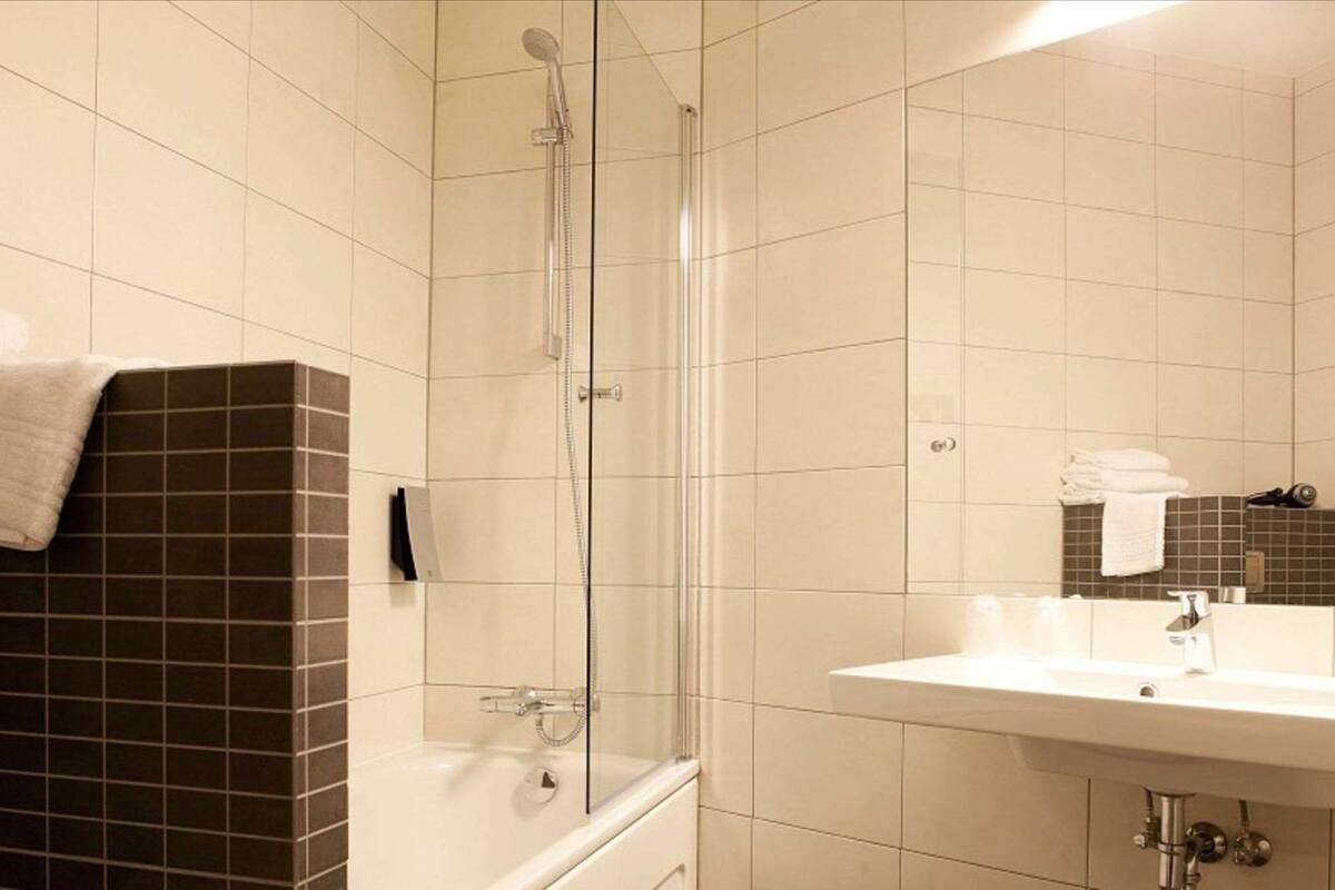 A bathroom with a glass-enclosed shower, a white sink, and a mirror.