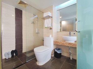 A modern bathroom with a glass shower enclosure, a white toilet, a sink with a mirror, and a towel rack.