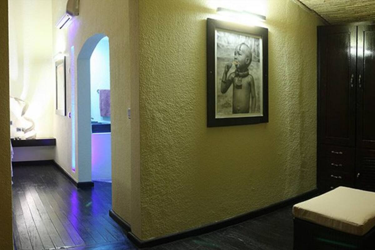 Quarto com sofá, mesa pequena, quadro na parede e armário de madeira.