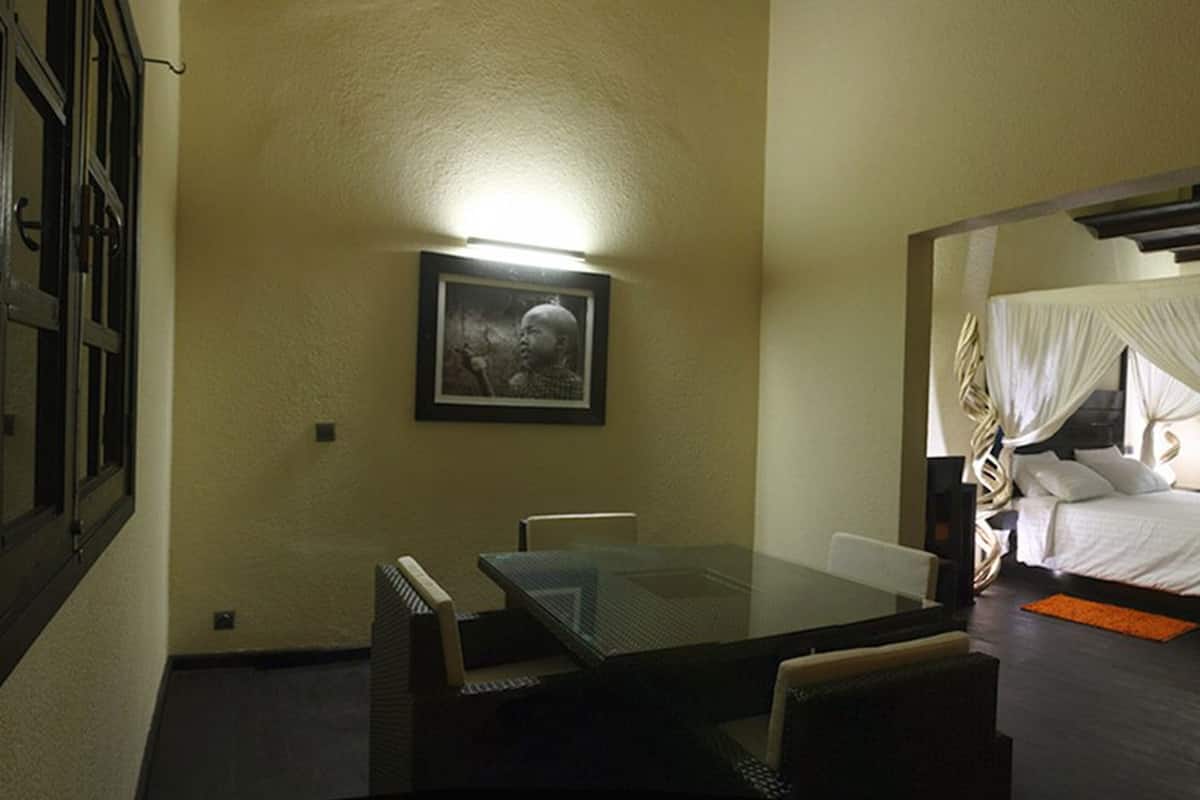 Quarto de hotel com cama, mesa de vidro e uma cadeira.