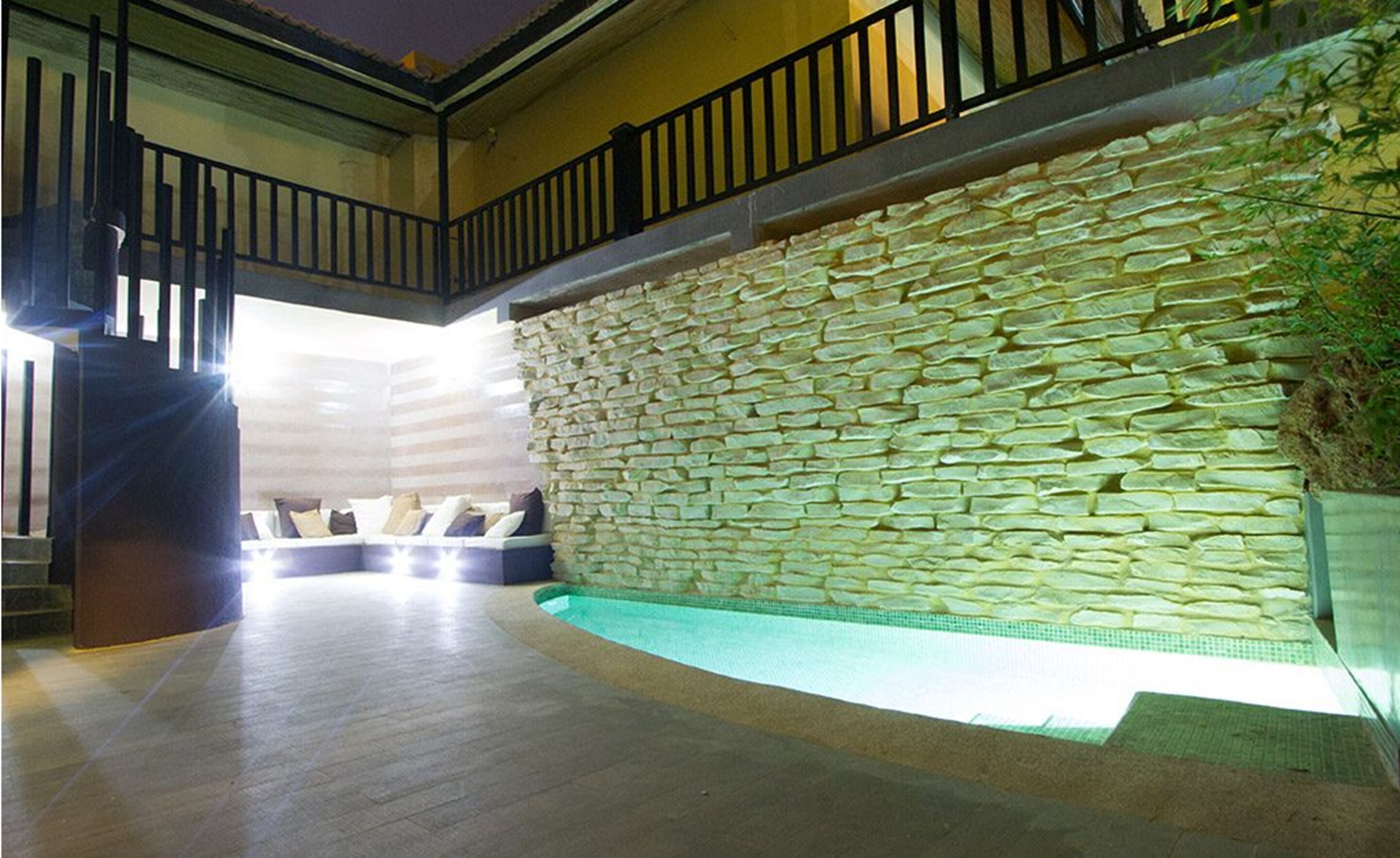 Amplio espacio interior con pared de piedra, piscina y escalera.