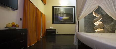 A bedroom with a bed, a dresser, a television, and a framed artwork on the wall.
